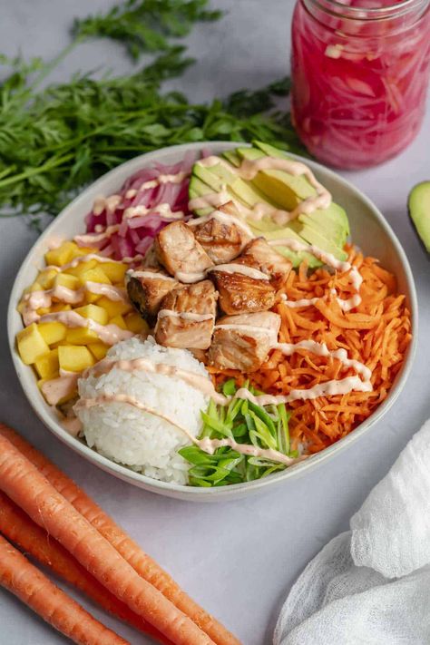 Looking for a healthy and delicious meal that's packed with protein and nutrients? Try this cooked salmon poke bowl recipe! The bowl features cooked salmon, rice, and a colorful array of fresh veggies like pickled onion, carrot, and avocado. The salmon is marinated in teriyaki sauce giving it a delicious Asian-inspired taste. This poke bowl is not only filling and nutritious, but it's also easy to make and customizable. Enjoy this tasty and wholesome meal for lunch or dinner! Powerbowl Lunch Recipes, Healthy Lunch Ideas Fish, Poke Bowl Lunch Prep, Poke Bowl With Salmon, Poke Bowls Salmon, Salmon Buddha Bowl Recipe, Sushi Salmon Bowl, Protein Bowls Lunch, Healthy Poke Bowl Recipe