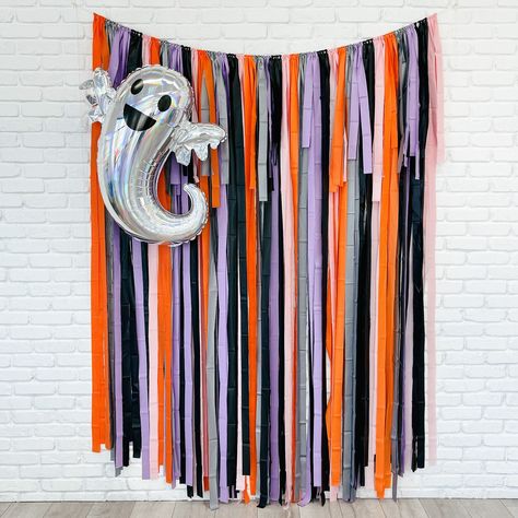 Set the stage for a spooktacular Halloween with our Halloween Fringe Backdrop. This vibrant backdrop features a mix of orange, gray, lavender, pink, and black fringe, adding a pop of color to your spooky celebrations. Available in a variety of sizes, it's perfect for photo booths and party decorations. Get ready to have some frightfully fun moments captured against this eye-catching backdrop. Colors: Orange, Gray, Pink, Lavender and Black Three sizes to choose from:  backdrop is approximately 7' in height and 4', 5', 6', 7' or 8' wide with extra rope on each side.  Our backdrops are weather-resistant, light-weight, and reusable for indoor and outdoor use. Easy to hang: You just need to unroll, tie a loop with the string and hang! We recommend using reusable command hooks to secure. **Due t Diy Backdrop Halloween, School Halloween Photo Backdrop, Halloween Streamer Backdrop, Halloween Party Backdrop Photo Booths, Halloween Party Picture Backdrop, Rainbow Halloween Decor, Halloween Streamer Ideas, Halloween Photo Backdrop Diy, Fringe Streamer Backdrop