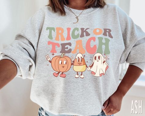 Retro Trick or Teach Halloween Sweatshirt xo Rock a classic fleece pullover with ribbed crew neck, long sleeve cuffs, and a flat hem. Layer it up or wear it on its own for a contemporary streetwear look. ♥ 》 》SIZING 《 《 These are unisex sweaters. They fit true to size. 》 》PLEASE NOTE 《 《 Ships in 2-7 business days. 》 》 ANATOMY OF OUR SHIRTS 《 《 * Brand: Gildan 18000 * 50% cotton, 50% polyester * Pre-shrunk * Classic fit * 1x1 athletic rib knit collar with spandex * Air-jet spun yarn with a soft Fall Tee Shirt Designs, Fifth Grade Teacher Outfits, Athletic Teacher Outfits, Teacher Fall Shirts, Diy Teacher Shirts, Teacher Halloween Outfits, Autumn Teacher Outfits, Cute Fall Teacher Shirts, Cricut Teacher Shirts