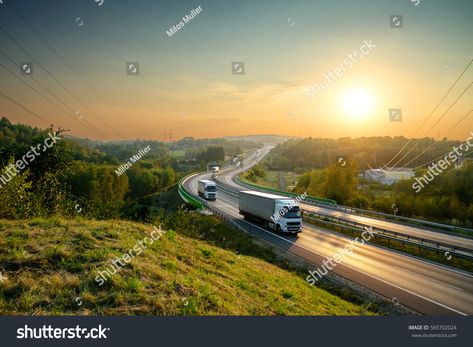 White trucks driving on the highway winding through forested landscape at sunset. Royalty Free image photo Driving Highway, White Trucks, Michigan Road Trip, Moving Cross Country, White Truck, Mitsubishi Motors, Long Haul, Public Service, Truck Driver