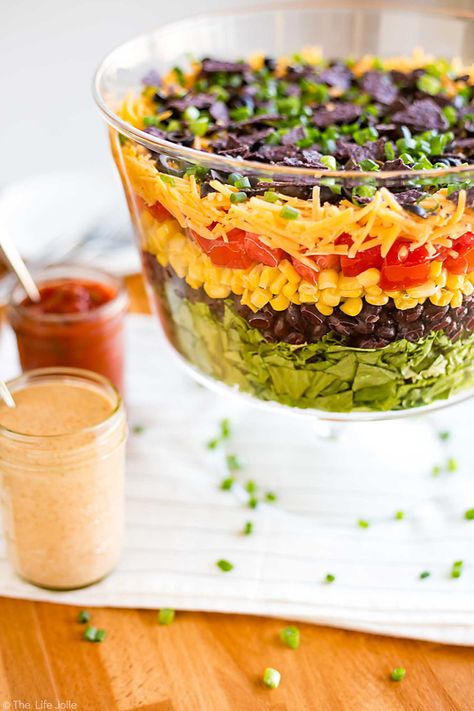 This 7 Layer Taco Salad is an easy recipe to make for parties. Full of delicious Mexican-inspired flavors it's got seven (or more) layers of things like beans, cheese, corn, tomatoes and is served with a creamy taco ranch dressing. Top it with chicken for a healthy main dish or serve it on it's own as great side dish to pass. This is perfect to bring to a Cinco de Mayo get together!