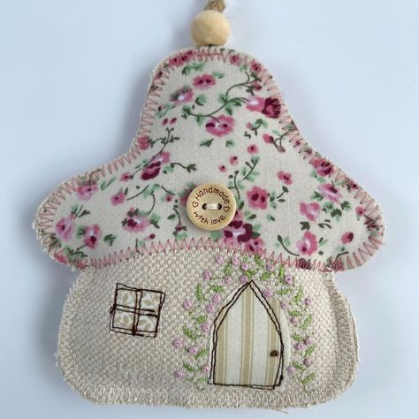 Cream and pale pink mushroom house hanging decoration. This lovely decorative toadstool house has been made from cream upholstery fabric, with a floral print fabric overlaid for the mushroom top/roof. The pretty print fabric is cream with a ditsy floral pattern in shades of pink and green. I’ve embellished the mushroom top by adding a natural wood button with the words “Handmade with love” and two tiny hearts inscribed on it. The toadstool house stem has an arch-shaped door in cream and beige st Handmade Applique, Fabric Houses Pattern, Fabric Mushroom, Toadstool Embroidery Patterns, Mushroom Applique Quilt, Felt Mushroom House, Fabric Toadstool, Embroidered Toadstools, House Quilt Patterns