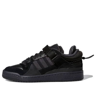 Looking for a stylish and comfortable shoe to rock both on and off the court? Look no further than the Bad Bunny x adidas Forum Buckle Low. This sneaker delivers Bad Bunny's stealthy interpretation of the vintage hoops shoe, with a blacked-out upper in a mix of leather, suede and textile. It's secured with a combination of traditional laces, a removable buckled strap, and a wraparound cord and lace lock at the heel, and features double tongue construction for a bilingual look. The upper tongue tag also features the third eye graphic seen on the cover of Bad Bunny's debut album. The sneaker is made with a black leather upper and mounted on a black rubber cupsole. The sneaker has an exposed EVA wedge on the medial side, which adds to the style of the shoe. (SNKR/Skate/Unisex/Low Top/Non-Slip Bad Bunny Shoes, Bad Bunny Adidas, Adidas Bad Bunny, Black Adidas Shoes, Eye Graphic, Bunny Shoes, Adidas Forum, Bunny Outfit, Bad Bunny