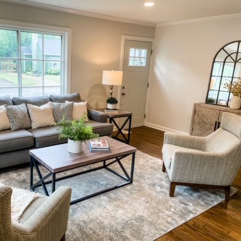 A gray family room with a gray sofa and cream sofa chairs. We used simple décor to stage the space. We added greenery, books, mirror, and cream décor. The items we chose allowed the space to shine. Gray Couch Living Room Accent Chair, Light Grey Couch Living Room With Accent Chairs, Grey Couch And Accent Chair, Grey Couch With Accent Chair, Gray Family Room, Sitting Room Ideas Cozy, Dark Grey Sofa Living Room, Grey Family Rooms, Living Room Redesign