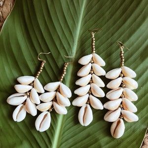 "For those who are forever drawn to the ocean and guided by the goddess spirit of Mami Wata... Each pair is made with smooth natural cowrie shells and brass African beads, hand picked and placed to create a beautiful cascading cowrie design. Available in 2 lengths: 3.5\"(3 Rows) or 4.5\" (5 Rows) DETAILS: Brass + Cowrie Shells Lengths: 3.5\" or 4.5\" Lightweight Packaged for gift giving. *Sold individually. Return to shop: Afrohemien.etsy.com Like and Follow Afrohemien for updates, sales, coupo Mami Wata, Cowrie Shell Jewelry, Wire Crochet Jewelry, Diy Earrings Polymer Clay, Bahama Mama, Pearl Accessories, Hawaiian Jewelry, Cowrie Shells, Polymer Clay Jewelry Diy