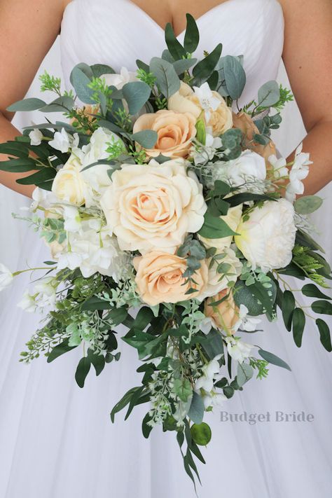 This lovely assortment of ivory, sand, and white is bound to turn heads on your wedding day. Composed of stunning roses alongside white peonies and greenery, this cascading brides’ bouquet from the Frankie collection is an absolutely breathtaking arrangement for any bride to be. This bouquet is 10” wide, 18” long, and is crafted by hand by our in-house florists. If you love the style of this bouquet but you have chosen a different accent color, keep in mind that color changes are free of charge. Fake Flower Bride Bouquet, August Wedding Flowers Bride Bouquets, Bride Bouquets Simple, Bridal Bouquet White With Greenery, Small Bridesmaid Bouquets, Peach Bouquet, Neutral Wedding Flowers, Peach Wedding Flowers, Cascading Bridal Bouquets