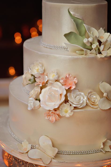 Three-Tier Wedding Cake With Champagne-Colored Luster Dust Floral Decorations Champagne Color Wedding Cake, Champagne Colored Wedding Cake, Champagne Colored Cake, Bridesmaid Dresses Cream, Wedding Colors 2025, Champagne Wedding Cake, Champagne Wedding Cakes, September Wedding Colors, Ceremony Arch Decor