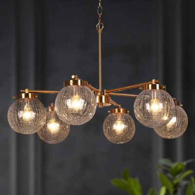 As a source of light and the focal point in any space, chandeliers are experts at fusing function with fashion. With a simple design and distinctive line, this beautiful mid-century modern chandelier features a wagon wheel arm that holds textured glass globe shades downwards and an electroplate gold finish to best match your style. Six E12/candelabra, max 40W bulbs (sold separately) are housed and travel through the textured glass globe shades to diffuse unique light. Brimming with mid-century f Gold Dining Room, Dining Room Light Fixture, Mid Century Modern Chandelier, Gold Globe, Island Chandelier, Wheel Chandelier, Chandelier Metal, Unique Chandeliers, Dining Room Light Fixtures