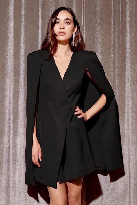 Make a statement in this fabulous Raquel Tux Cape Dress. Show off your drama queen side with this cape dress, featuring an asymmetrical closure. Perfect for your next big event - fun and flirty, you're sure to slay the crowd! Blazer dress Cape Mini V-Neck Lined Length: 34 1/2" Chest: 17" Waist: 15 1/4" Lined Self: 100% Polyester Lining: 100% Polyester Hand wash cold with similar colors. Do not tumble dry, iron, or dry clean. Model is wearing a size S  Style #: F2310D5693 Cape Blazer Outfit, Cape Overcoat, Cape Sleeve Blazer, Cape Blazer, Prom Outfit, Dress Cape, Clothing Reference, Drama Queen, Tuxedo Dress