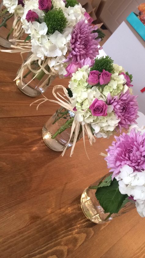 Engagement Party center pieces I made. They are perfect for an outside event or spring. I used big mason jars, hydrangeas, mums disbud, trachelium and rose sprays. They came out beautiful. Perfect DIY bridal shower, rehearsal dinner, flower arraignments. I used raffia to make bows around the mason jars. The colors looked amazing together: white, green, pink and light purple, lilac. Purple Bridal Shower, Decorative Bottles, Tafel Decor, Spring Bridal Shower, Bridal Shower Tables, Bridal Shower Centerpieces, Bridal Shower Diy, Diy Event, Diy Shower