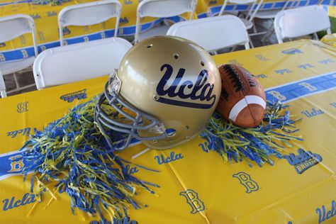 UCLA football centerpiece- I used old helmets and spray painted them to match. I went to a decal shop to have the UCLA logo made. They came out awesome!!! Parade Float Football Theme, Helmet Centerpiece, Football Banquet Backdrop, Gold Football Theme, Ucla Party Decorations, Football Lantern Centerpieces, Ucla Logo, Pom Pom Centerpieces, Football Banquet Centerpieces