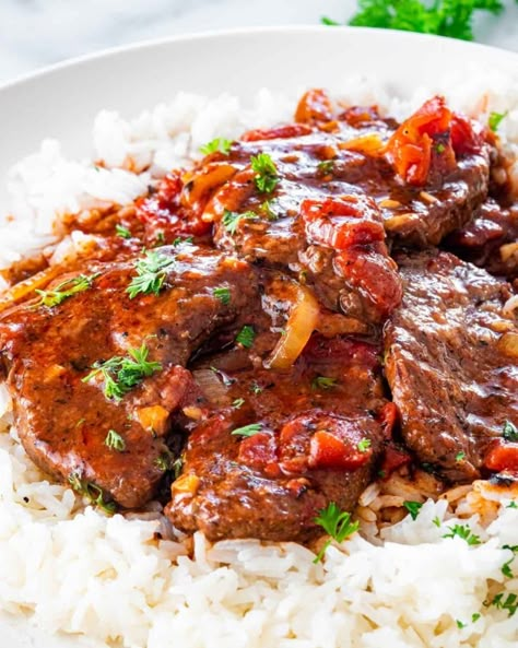 This Easy Swiss Steak recipe is made with inexpensive beef, cooked down until tender in a flavorful tomato sauce. Made all in one pot, an impressive steak dinner doesn't have to cost you so much money and effort! #swisssteak #recipe Swiss Steak Recipes With Stewed Tomatoes, Cube Steak With Tomato Gravy, Steak And Tomatoes, Beef Too Round Steak Recipe, Recipe For Cubed Steak, Slow Cooker Swiss Steak Recipe, Swiss Dinner Recipes, Swiss Steak With Tomato Gravy, Beef And Tomato Recipes