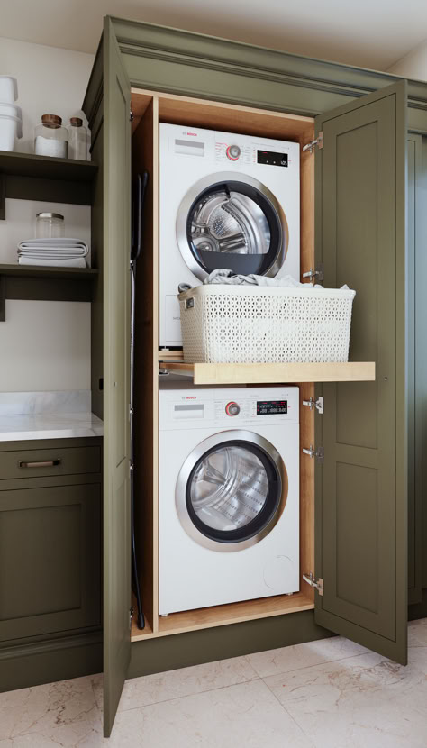 Compact laundry room upstairs with stacked washing machine and tumble dryer, green cabinetry, and pull-out shelf. Stacked Washer Dryer Hallway, Lift Washer And Dryer, Hallway Washer And Dryer Closet, Cabinet For Stacked Washer And Dryer, Double Stack Washer And Dryer, Stacked Laundry Small Space, Laundry Room Remodel Stacked Washer Dryer, Bathroom Stackable Laundry Combo, Pull Out Laundry Shelf