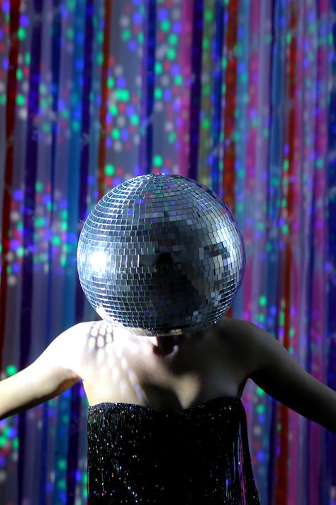 Woman wearing a disco ball headpiece in front of a colorful background Disco Ball Hat Diy, Disco Ball Headpiece, Diy Mirror Ball, Disco Girl Costume, Disco Ball Hat, Make A Disco Ball, Disco Ball Head, Diy Disco Ball, Giant Mirror