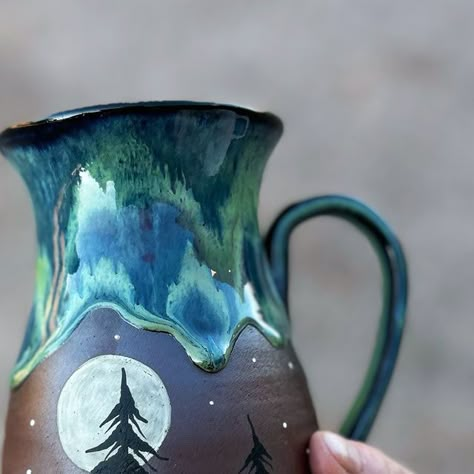 SamandMo Pottery on Instagram: "Natural light shows off the colors on this Northern Lights mug and its nice chunky drips!😊 we will have some more of these available in our April restock 😊  #northernlightscanada #northernlights #northernlightsart #tree #treelovers #forest #mug #cup #art#handpainted #pottery #ceramicmug #rustic #unique #ceramics" Drawing On Pottery, Northern Lights Canada, Forest Mug, Northern Lights Art, Pottery Items, Glaze Combinations, Tree Mug, Pottery Inspo, Ceramic Glazes