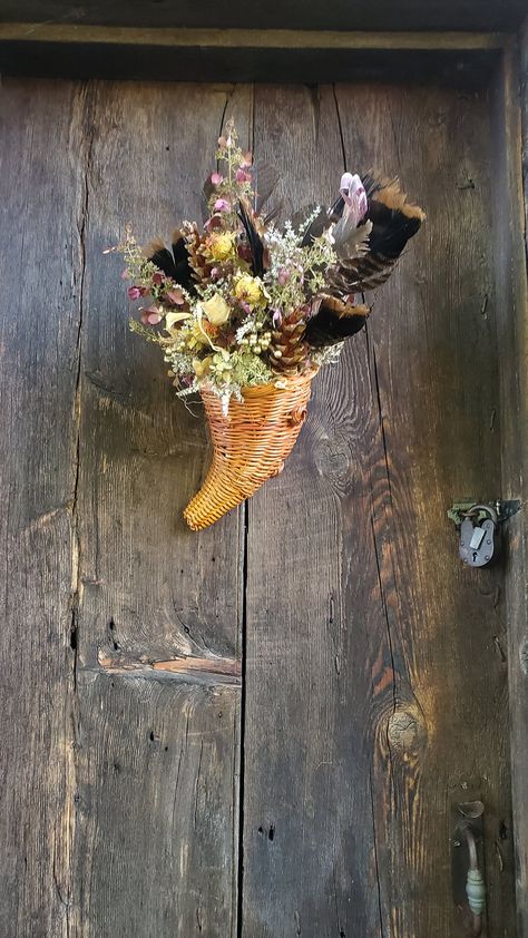 The cornucopia is the traditional symbol for abundance and harvest. It the perfect Thanksgiving decoration. This hanging, wicker basket, cornucopia has been filled  with hydrangeas,  real turkey feathers,  german statice, pine cones and a few faux berries in gold. The curved, cone shaped basket itself measures about 10 inches tall.  The completed arrangement is about 18  inches long and spans about 10 inches across at its widest point.  Don't want to hang it? It will also sit and serve as a cent Cornucopia Basket Decor, Crescent Cornucopia, Paper Mache Cornucopia, Symbol For Abundance, Cornucopia Bread Basket, Thanksgiving Table Arrangements, Small Boxwood Wreath, German Statice, Cornucopia Basket