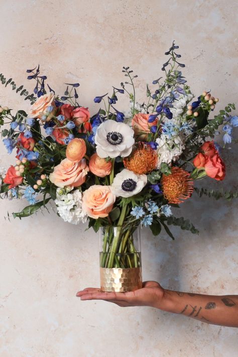 “On the Yam” is a 360° vase arrangement featuring forty-ish farm fresh flowers plus a flourish of foliage. Expect roses, anemones, delphinium and more in a petal palette of soft blues and pleasant peaches with pops of orange and white! Fall Flowers With Blue, Bouquet Of Flowers Fall, Fall Wedding Flowers With Blue, Blue Orange Flower Arrangements, Bright Fall Flower Arrangements, Orange And White Wedding Flowers, Wedding Flowers Blue And Orange, Wedding Blue And Orange, Blue White Orange Flower Arrangements