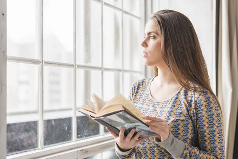 Beautiful young woman standing near the window holding book in hand looking away Photo | Free Download Person Holding Book Reference, Holding Book Pose, Person Holding Book, Holding Book Reference, Woman Holding Book, Gesture Practice, Rendering Reference, Film Moodboard, Anatomy Tips