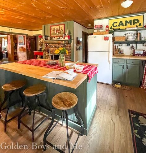 Cabin kitchen with fireplace and Benjamin Moore Backwoods paint - www.goldenboysandme.com Cabin Painted Furniture, Maximalist Cabin Decor, Cabin Theme Kitchen, Diy Cabin Kitchen, Up North Cabin Interior, Retro Cabin Kitchen, Lake Cabin Kitchen Ideas, Vintage Lake Cabin, Interior Cabin Colors