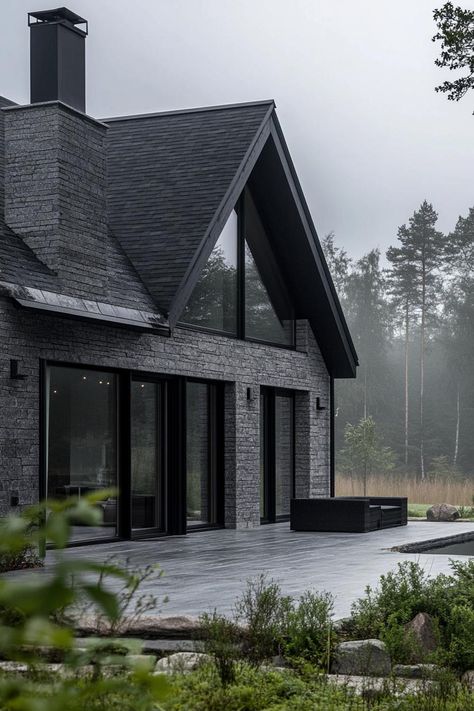 Modern barndominium house grey stone facade with black trim misty Scandinavian forest views. Check out the coolest dark barndominium houses that combine rustic charm with modern sophistication, enhancing a living space with bold hues and sleek designs. All Black Exterior House, Dark Barndominium, Dark Grey House Exterior, Scandinavian House Design Exterior, Black Home Exterior, Barndominium Houses, Dark Grey Houses, Modern Mountain Cabin, Scandinavian House Design