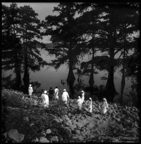 Baptism, Moon Lake, MS 1997. A group of baptism candidates make their way carefully over loose stones to the edge of Moon Lake, an oxbow of the Mississippi near Lula, MS. Small churches in the Lula/Friars Point area gather in the fall to baptize candidates in the lake just as they have for over one hundred years. The great migration of blacks from the Delta in the 1940’s and 50’s resulted in a dramatic decline in the Delta population, impacting church congregations to the point that many churches were abandoned. Today’s Delta churches now pool their resources to help keep tradition alive. Baptisms are usually attended by members of 3-6 different congregations. Small Town Names, Great Migration, The Great Migration, Mississippi Delta, Blog Art, Southern Gothic, Loose Stones, Mississippi River, Fine Art Gallery