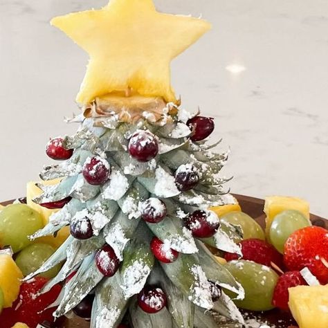 Kelsi || Content Creator on Instagram: "🎄 Christmas Tree Fruit Platter 🎄⁣ ⁣ This is THE cutest and easiest way to serve fruit at all your holiday parties!! Cut the stem off the pineapple and turn it upside down to make a Christmas tree!! I added cranberries as ornaments, a pineapple star on top and powdered sugar as snow! Inspo from the amazing ⁣@created.at.home .⁣ .⁣ .⁣ .⁣ #christmas #christmastree #christmasideas #christmastime #christmasinspiration #christmasinspo #holiday #christmasdiy #diychristmas #holidayhosting #holidayhome #christmasrecipes" Pineapple Xmas Tree, Pineapple Christmas Tree Fruit Display, Pinapple Tree Christmas, Pineapple Serving Ideas, Pineapple Top Christmas Tree, Pineapple Christmas Tree Fruit Tray, Pineapple Tree Fruit Display, Fruit Christmas Tree Platter, Christmas Tree Fruit Platter