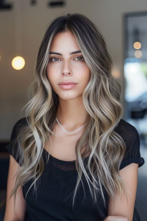 Woman with long wavy hair wearing a black shirt and necklace, standing indoors. Shades Of Brown Balayage, Ash Blonde On Brown Hair, Dark Brown Hair With Ash Blonde Highlights, Brown Hair Fade, Brown Hair With Ash Blonde Highlights, Ash Brown Hair Dye, Ash Brown Hair Balayage, Brown With Caramel Highlights, Ashy Blonde Hair