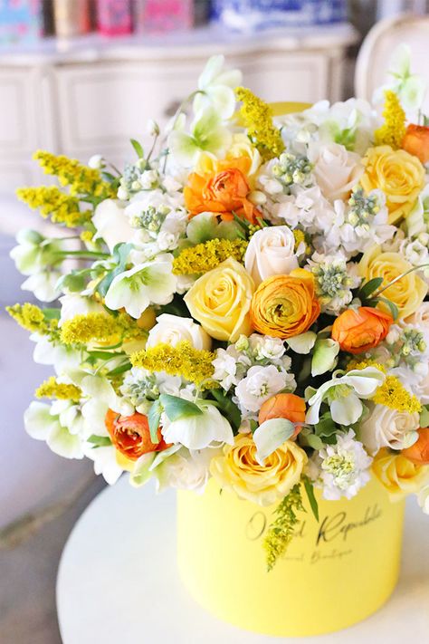 Like a ray of sunshine on a beautiful morning, this breathtaking floral arrangement showcases charming blooms in the most cheerful colors. Yellow roses and goldenrods send happy thoughts. Stocks and hellebores look refreshingly radiant in creamy white with hints of apple green. Orange ranunculus commands attention with its eye-popping hue. A fitting gift for birthdays, celebrations, or when someone needs a bit of cheering up, this beautiful creation is presented in a signature yellow hatbox. Fea Thank You Flowers Arrangement, Yellow And White Flower Arrangements, Yellow Flowers Arrangements, Yellow Flowers Decoration, Orange Floral Centerpieces, Yellow Floral Arrangements, Fake Flower Arrangements Diy, Yellow Flower Bouquet, Yellow Flowers Bouquet