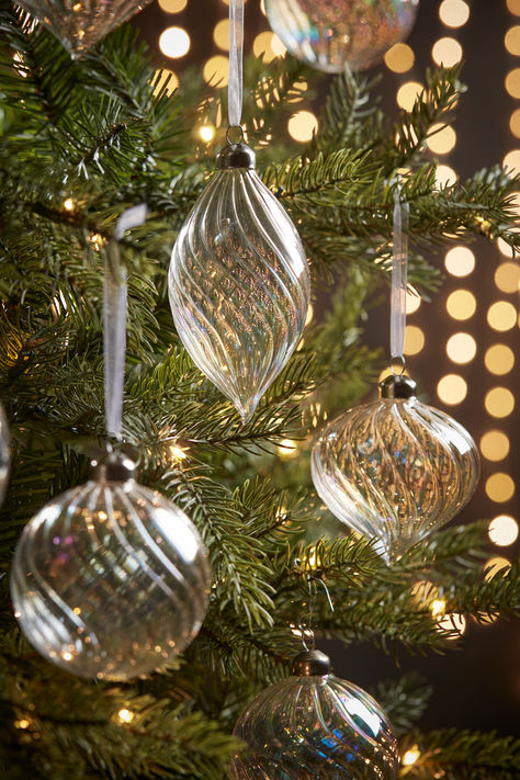 In three different shapes, our selection of 12 glass iridescent baubles are the perfect addition to an elegant and minimalist tree.  Curved fluting around each shape adds a softness to the glass, whilst the iridescent hues shine beautifully under the warm glow of your tree lights. Remote Control Candles, Iridescent Christmas, Minimalist Tree, Tree Candles, Orchid Flower Arrangements, Clear Glass Ornaments, Crystal Christmas Tree, Glass Sphere, Bauble Ornaments