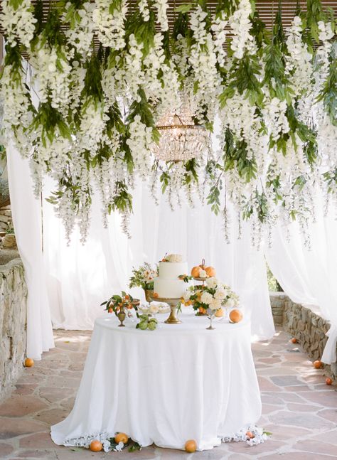 A fairytale inspiration: http://www.stylemepretty.com/2015/08/27/fashion-to-table-citrus-inspired-wedding-details-with-late-afternoon/ | Photography: Rebecca Yale - http://rebeccayalephotography.com/ Wedding Hanging Flowers Back Drop, Chandelier Wedding Foliage, Wedding Pergola Candles, Wedding Floral Chandelier Babies Breath, Hanging Flowers Pergola Wedding, Barn Wedding Hanging Flowers, Garland On Chandelier Wedding, Cake Table Flower Garland, Winter Floral Chandelier Wedding