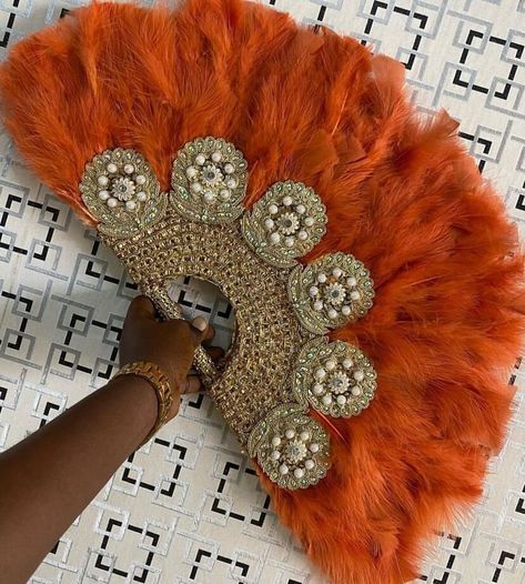 Orange Gold Feather Hand Fan, Clutch Semi-Circle African Traditional Wedding Bridal Hand Fan, Nigerian Wedding Hand fan  NEED OTHER DESIGNS AND COLOURS OF HAND FANS, BRAIDED WIGS, AUTOGELE HEADWRAPS AND AFRICAN CORAL BEADS, VISIT OUR ETSY SHOP HERE: https://sereneafrica.etsy.com This beautifully crafted African bridal accessory adds spice to your outfit on your wedding day. It can also be used by guests at a wedding. Production/ processing time is 1 week. We use DHL Express, it takes 3-5 busines African Hand Fans, African Wedding Headwrap, Nigerian Feather Fan, Bridal Handfan Nigeria, Orange Traditional Dresses African, Feather Fans Wedding, Nigerian Fans For Wedding, African Feather Fan, Nigerian Hand Fan