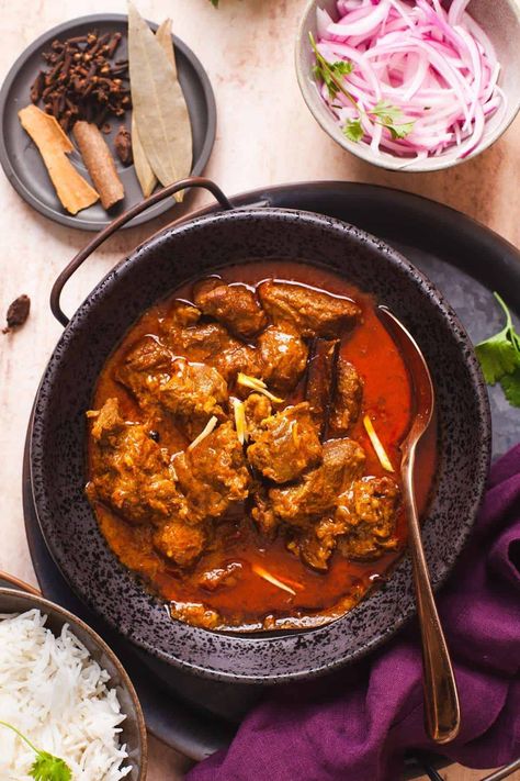 Indian lamb curry served in a black dish with rice and sliced onions on the side. Spicy Lamb Curry, Lamb Chop Recipes Indian, Indian Lamb Curry Recipes, Lamb Chunks Recipes, Lamb Curry Recipes Indian, Indian Lamb Recipes, Lamb Recipes Indian, Indian Lamb Curry, Punjabi Dishes