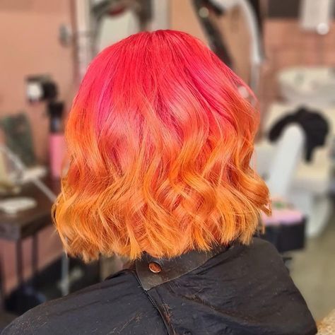 This pin is a picture of a curly long Bob hairstyle from behind. The hair is bright pink at the top and ombré fades to orange. Pink And Orange Hair Ombre, Pink Orange And Yellow Hair, Silver And Orange Hair, Half Pink Half Orange Hair, Orange To Pink Hair, Pink To Orange Hair, Orange And Pink Hair, Orange Pink Hair, Pink Orange Hair