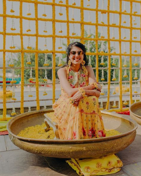 bride at her haldi with a unique decor Outfit For Haldi Function For Bride, Bride Haldi Outfit, Haldi Outfit Ideas For Bride, Haldi Dress Ideas For Bride, Bridal Haldi Outfit Indian, Haldi Backdrop, Haldi Decoration, Haldi Decor, Haldi Ceremony Outfit For Bride