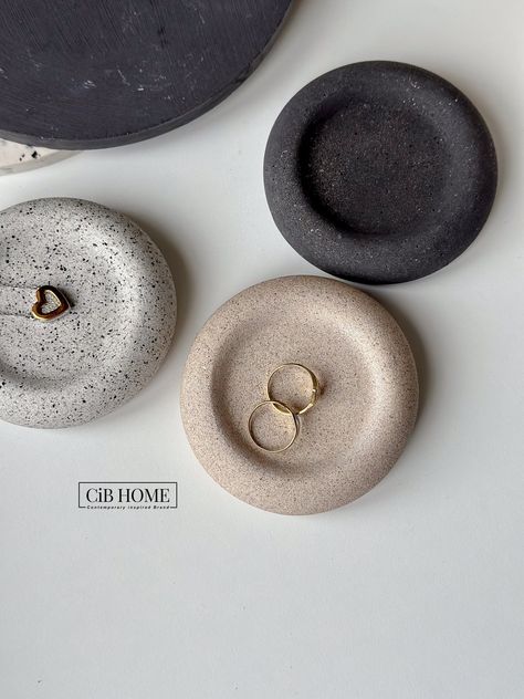 Embrace the beauty of simplicity with our Scandinavian Pebble Jewellery Plate. This small slate tray, meticulously crafted from jesmonite, captures the essence of nature with its stone-like texture. Whether you're curating a bohemian, minimalist, or eclectic vibe, this plate seamlessly adapts. It's a small circle of styling versatility that effortlessly complements various decor styles. ~ Product Details ~ Size:  9cm in length, 9cm in width, and a height of 3.5cm Materials: Made with Jesmonite This compact tray embodies minimalist charm. Mixed, poured, and sealed by hand, each plate is a unique piece of functional art. Use it to hold tealights or votive candles, creating a warm, ambient glow. It's also an ideal spot to store and display small items like slim necklaces, rings, or other cher Jewellery Plate, Candle Products, Pebble Jewelry, Minimalist Bohemian, Plates Diy, Candles Photography, Ceramic Tray, White Granite, Ceramic Candle Holders