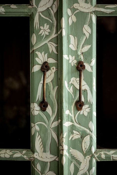 A masterpiece of craftsmanship and design collaboration, the Birdie pieces feature a delicate scene depicting birds and vines, designed in-house and beautifully executed in India. Featuring a hand painted pattern atop HMcG colour Hampstead Green, glazed double doors with antique gold hardware, charming saber legs, three shelves and original teak interior. #handpainted #antiquefurniture #rusticfurniture #furnituredetails #brasshardware #greenfurniture Diy Paint Wardrobe, Painted Cabinet Interior, Gold Doors Painted, Diy House Paint Interior, Hand Painted Doors Ideas, Pattern On Pattern Interior Design, Mushroom Painted Furniture, Green Painted Furniture Ideas, Antique Interior Doors