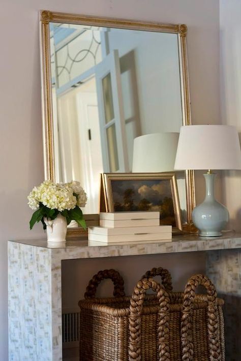 Chic foyer with large woven basket tucked under stone waterfall console table filled with silver and gold mirror, baby blue lamp, cream lacquered boxes and art. Entrance Foyer Design, Large Woven Basket, Leaning Mirror, Foyer Decorating, Entrance Foyer, Foyer Design, A Mirror, Entryway Decor, Interior Inspiration