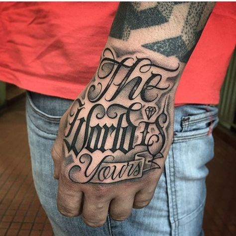 The World Is Yours Hand Tattoo, Rip Hand Tattoos, Hand Tattoos For Guys Men Design, Hustle And Motivate Tattoo, The World Is Mine Tattoo, Lettering Hand Tattoo, Ambitious Tattoo, Hand Tattoo Designs Men, Best Hand Tattoos Men