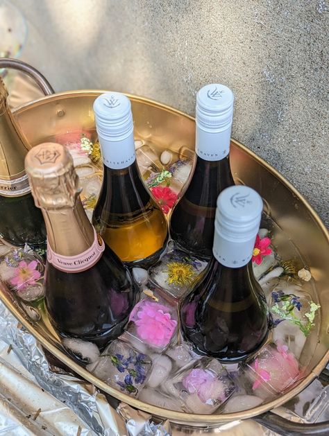 Champagne and white wine bucket with floral ice cubes Wine Display For Party, Ice Champagne Bucket, Ice Bucket Wedding, Ice Bucket For Party, Champagne Bucket Flowers, Wine Bucket Ideas, Wine Table Display, Wedding Ice Bucket, Folklore Party