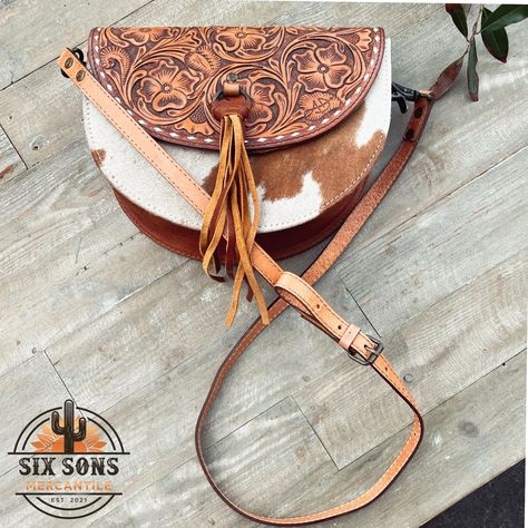 Handmade Genuine Full Grain Hand Tooled Leather and Hair On Cowhide Purse You are going to love this small, cute crossbody purse!  This is a perfect bag to dress up or down, great for any occasion. So much time and love went into this bag! ❤️ Dimensions: 7.5"H x 10.5"W x 3"D  Genuine Full Grain Leather Hand Tooled Leather Genuine Hair-On Cowhide Buck Stitch Detail Cotton Lining Adjustable Leather Strap Back Zipper Pocket Magnetic Flap Closure Hair-On Cowhide is a natural product and each hide has different shading, hair length and color making each bag unique in it's own way.  These bags come in assorted colors and patterns, we will do our best to accommodate specific hide requests but we cannot always, we are sorry! Each bag is meticulously guided through multiple stages, featuring a prop Cute Crossbody Purse, Western Tote Bags, Handmade Leather Purse, Cowhide Purse, Tooled Leather Purse, Western Purses, Color Making, Hand Tooled Leather, Tooled Leather