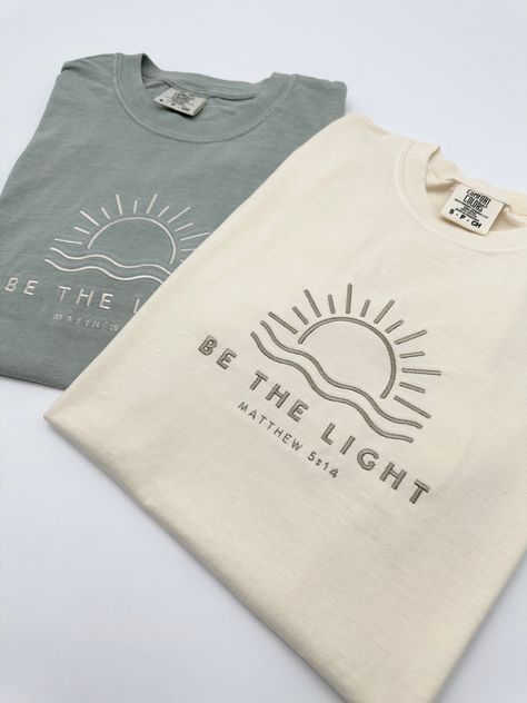 Embroidered Be The Light Matthew 5:14 Comfort Colors® Shirt | Inspirational Christian Tee | Religious Faith Clothing | Bible Verse Gifts The item in the first picture features Cream thread color on a Pepper Comfort Colors T-shirt. The item in the first picture features Sand thread color on a Bay Comfort Colors T-shirt. The item in the first picture features Doe Skin Beige thread color on an Ivory Comfort Colors T-shirt. The item in the first picture features Cream thread color on a Yam Comfort C Unisex Christian Shirt Ideas, Cute Jesus Shirts, Cute Christian T Shirts, Christian Tshirt Design Ideas Vinyl, Cricket Projects Craft Ideas Shirts, Christian Shirt Design Ideas, Merchandise Ideas Clothing, Men T Shirt Design Ideas, Christian Tshirts Designs Woman