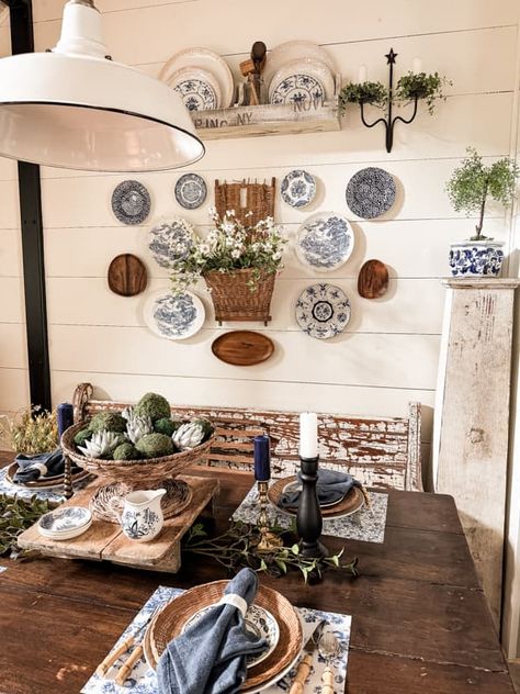 Decorate dining room wall with plate wall decor and vintage basket beside the farmhouse table. Plates And Pictures On Wall, Plates Around Picture On Wall, Dining Room Vintage Decor, Wall Collage With Baskets, Plates In Frames Wall Decor, Plate And Basket Wall, Decorating With Plates On Wall Ideas, Hanging Vintage Plates On Wall, China On Wall Hanging Plates