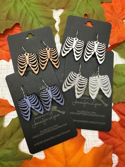 These boney rib cage earrings are laser engraved from either acrylic or maple ply. The result is a pair of spooky-fun earrings that are perfect for Halloween and all spooky season long!  OPTIONS INCLUDE:  - CHERRY WOOD - Laser cut from a piece of cherry ply, the engraved area is painted with a matte black that adds a distressed look to the wood.  - WHITE - Cut from a piece of white eucalyptus board. The white is slightly textured and the engraved portion is a dark brown. The backside of the earr Halloween Laser Ideas, Laser Printing Ideas, Laser Halloween Ideas, Unique Laser Cut Ideas, Xtool S1 Project Ideas, Halloween Laser Projects, Wood Laser Engraving Ideas, Laser Cut Projects, Laser Cut Halloween