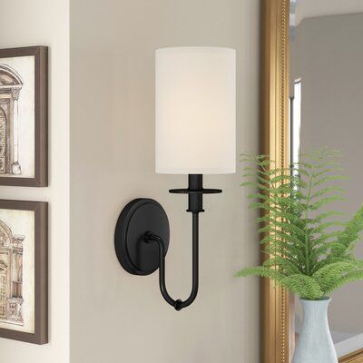 This 1-light-armed sconce has a simple design that's easy to mix in with your existing style and fixtures. It's made with a circular metal backplate and has a gooseneck arm that branches up into a candle holder. A neutral, cylindrical fabric shade surrounds the socket and diffuses the light from a 60W bulb (sold separately). We love that this sconce is compatible with dimmer switches, so you can get just the right light, no matter if you install it in your hallway or next to your bed. Finish: Ma Foyer Wall Sconces Entryway, Hallway Light Fixtures Wall, Hall Wall Sconces Hallways, Black Sconces Living Room, Mixing Light Fixtures, Fireplace Wall Sconces, Black Sconces Bathroom, Fireplace Sconces Lighting, Living Room Lighting Wall