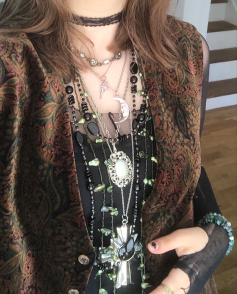 A mid-size person/girl wearing a black lace tank top, a green/red/orange patterned wide open waistcoat over it, a black ripped tights top under it, black corduroy pants, black platform dr. Martens and multiple crystal rings and bracelets. 	The person is also wearing multiple silver necklaces; one in form of a skull, a cross, and one in form of a moon, a long black bead and an even longer green bead necklace and a black lace choker. Whimsy Goth Outfit Men, Cupidcore Aesthetic Outfit, Whimsigoth Fashion Masc, Mens Whimsigoth, Eco Goth Aesthetic, Alt Outfits Pants, Green Necklace Outfit, Masculine Whimsigoth, Male Whimsigoth