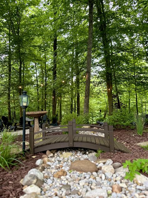 Dry creek bed in garden surrounding fire pit area. MY 2024 Small Bridge In Garden, Bed In Garden, Stream Landscaping, Creek Ideas, Landscape Island, Dry Stream, Ground Level Deck, Wooded Landscape, Dry Creek Bed