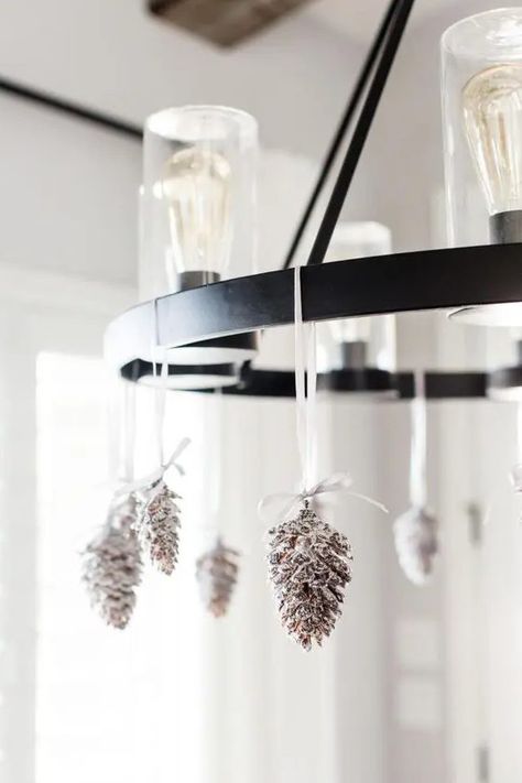 a bulb chandelier decorated with snowy pinecones is a cool and chic idea for the holidays, it's quite rustic Decorating A Chandelier, Zellige Tile Bathroom, Christmas Chandelier Decor, Christmas Chandeliers, Snowy Pinecone, Black Interior Door, Christmas Chandelier, Bulb Chandelier, Bathroom Chandelier