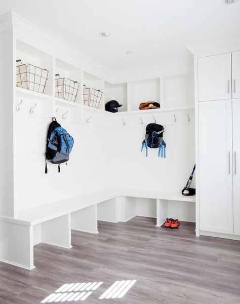 L-shaped bench is lined with a beadboard trim accented with satin nickel coat hooks positioned beneath shelves fitted with vintage metal ad canvas bins lit by recessed lighting. Beadboard Trim, Storage Bench With Baskets, L Shaped Bench, Mudroom Remodel, Mudroom Lockers, Diy Storage Bench, Room Storage Diy, Corner Seating, Mudroom Entryway