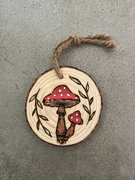 "This fun design is a spruce tree round with  mushrooms and leaves wood burned into it, painted with some colored pencil as well! It measures approximately 3.5\" x 3.25\" and already includes a twine hanging cord. Perfect for hanging on your wall, using as an ornament an much more! I have many other items you may be interested in so please check out my page!" Autumn Wood Burning Ideas, Wood Burn Keychain, Wood Burn Ornaments Tree Slices, Wood Burning Mushrooms, Fall Wood Burning Ideas, Painted Wood Rounds, Mountain Wood Burning, Wood Burning Art For Beginners, Mushroom Wood Burning