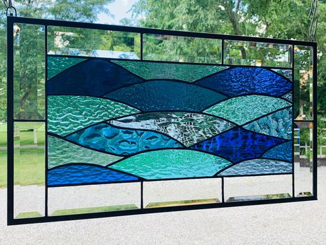 This beautiful abstract stained glass panel is made from an assortment of turquoise. blue and white wispy glass in a variety of shades and textures. Panel is framed with a clear beveled border which is designed to capture and refract the light. It measures 12.5 inches by 22.5 inches. Reminiscent of Stained Glass Ocean Theme, Abstract Stained Glass Designs, Beach Theme Backyard, Stained Glass Ocean, Stained Glass Garden Art, Stained Glass Bevels, Beach Colors, Glass Art Pictures, Stained Glass Window Film